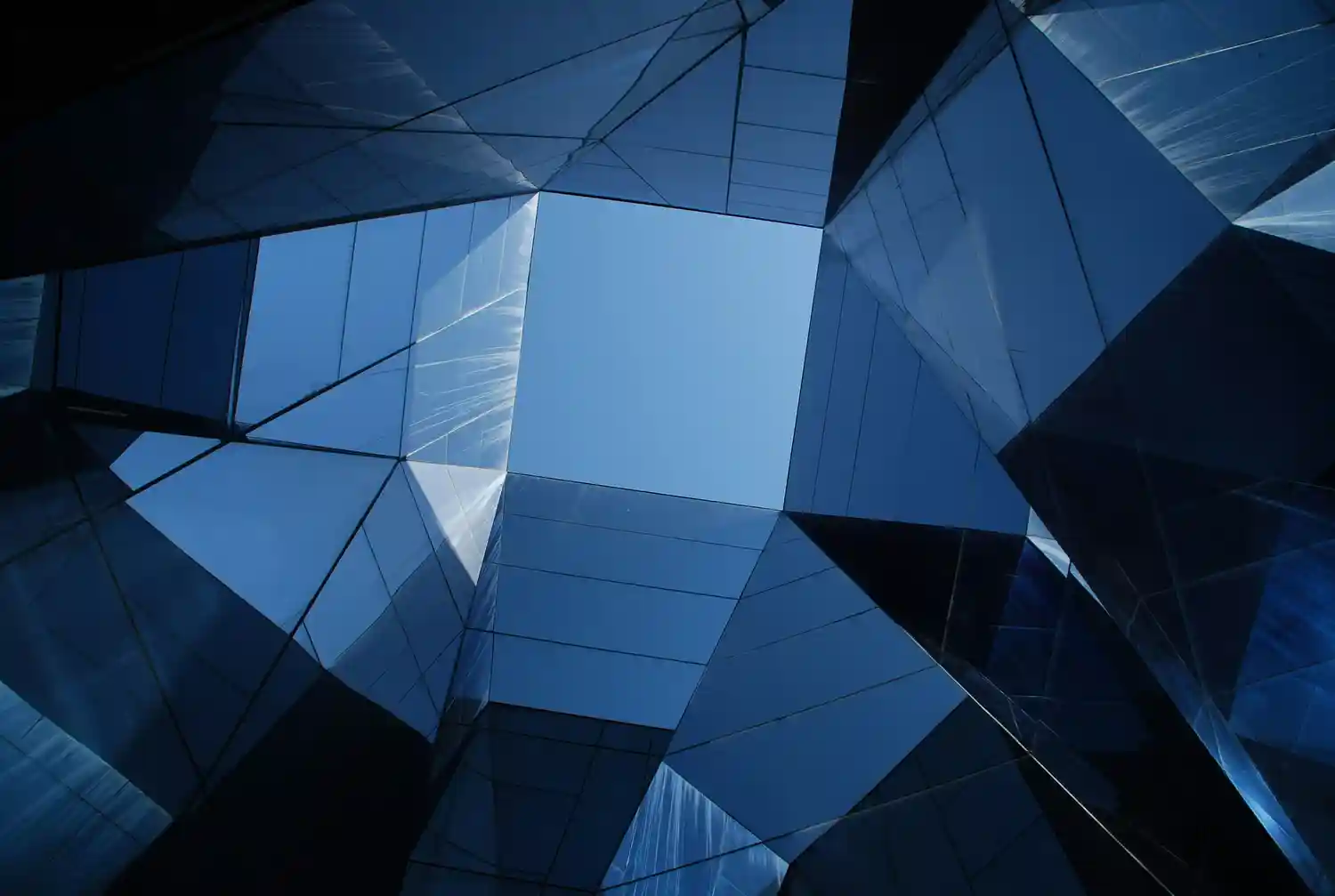 A modern office building with a smooth, blue-tinted glass facade reflecting the sky. The transparent exterior symbolizes the shift toward clear, audit-ready AI governance and structural predictability under the EU AI Act.